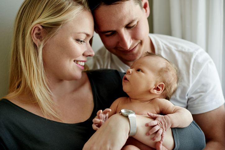 A happy couple holding their newborn baby after undergoing IVF cycle with PGT-A testing.